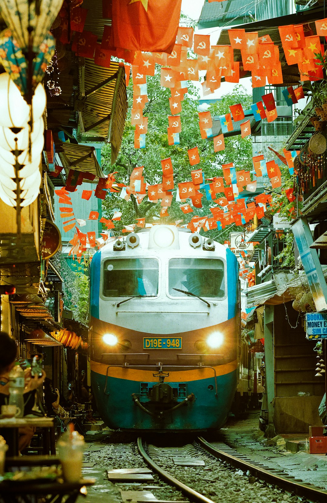 Hanoi Train Street decorated with Vietnamese flags as a train passes